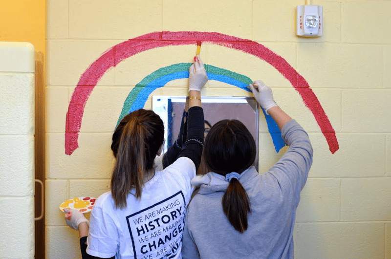 Two student volunteers helping to paint their school